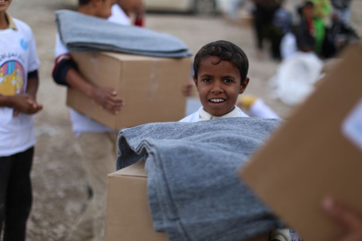 Junge trägt Karton mit Hilfsgütern